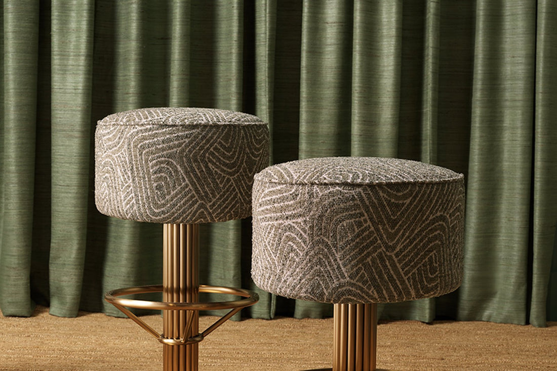 Zwei elegante Barhocker vor grünem Vorhang