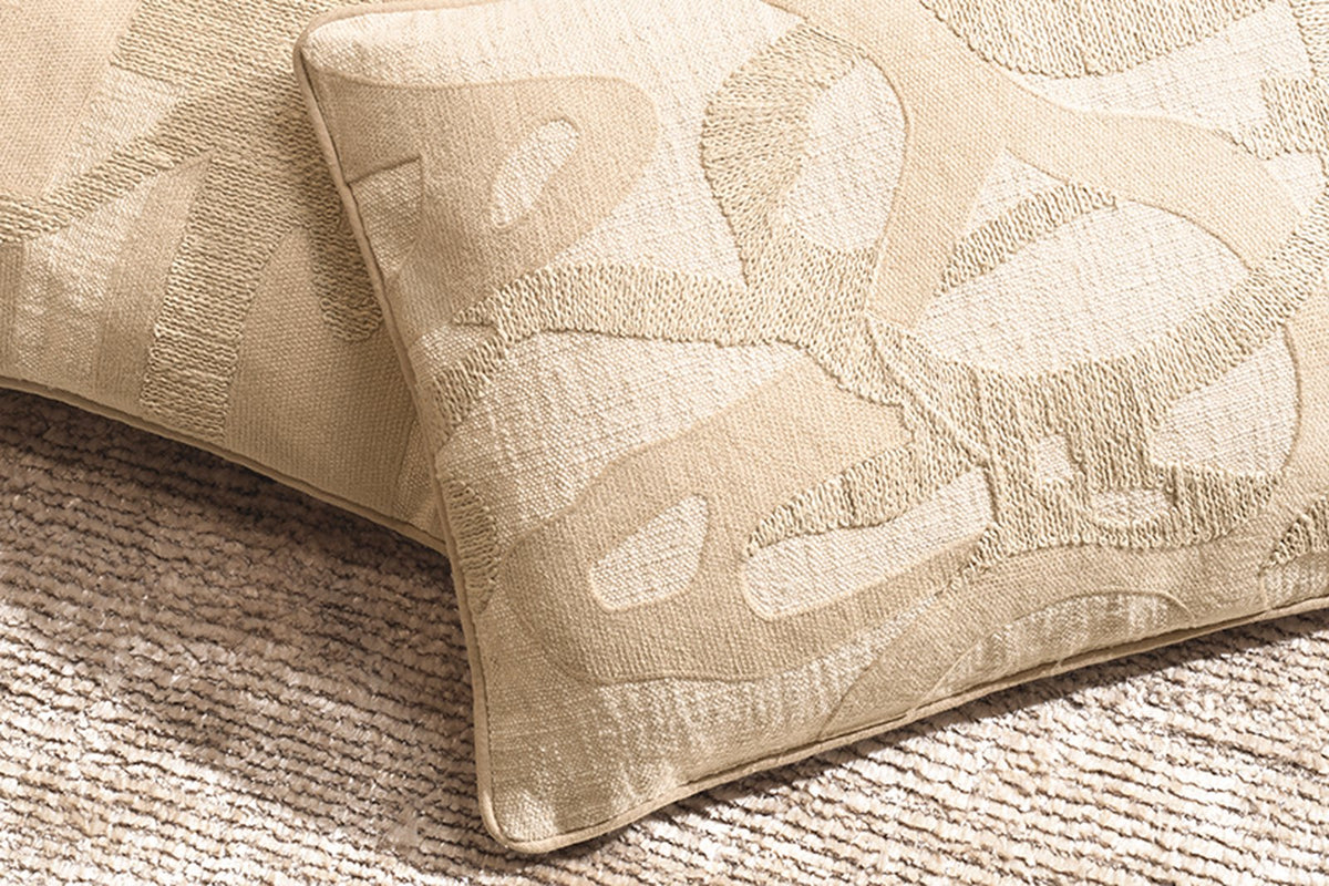 Beige Kissen mit abstraktem Muster auf Teppich