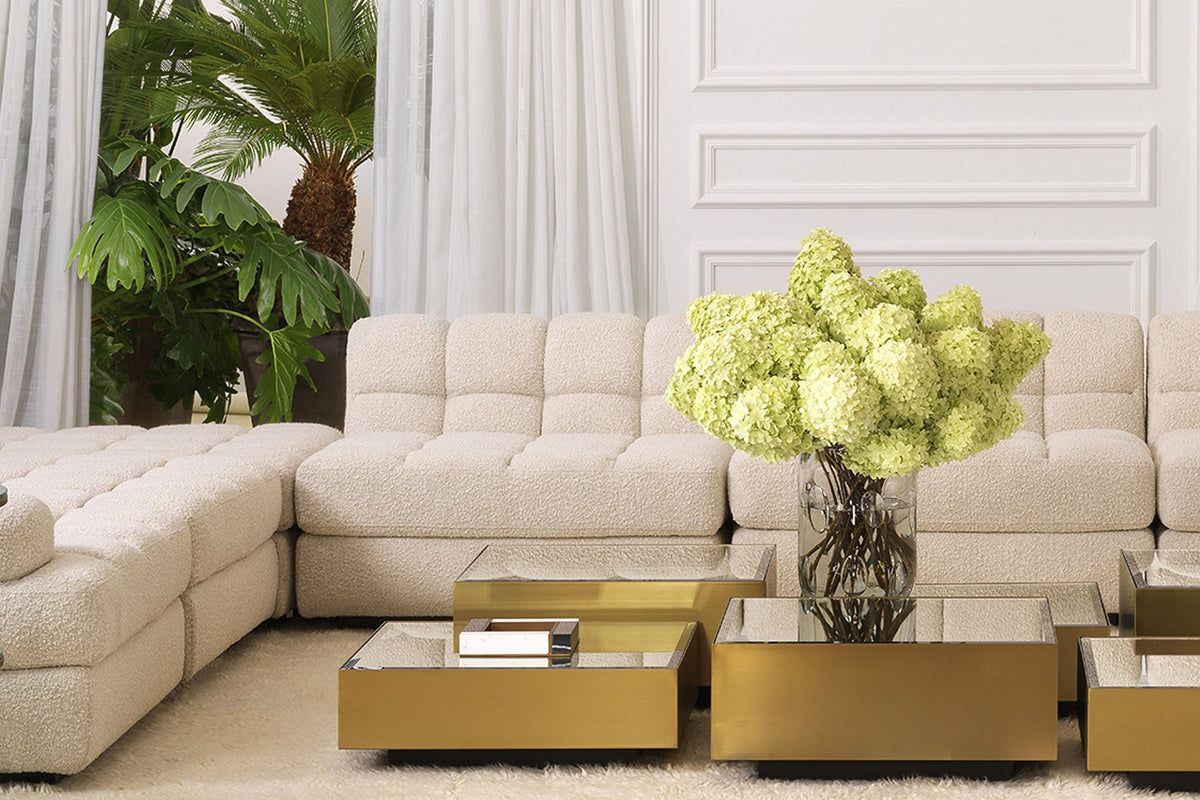 Elegantes Wohnzimmer mit modularem Sofa und goldenen Tischen